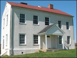 White two-story stucco building with red metal roof.