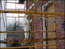 Scaffolding touches a brick building.