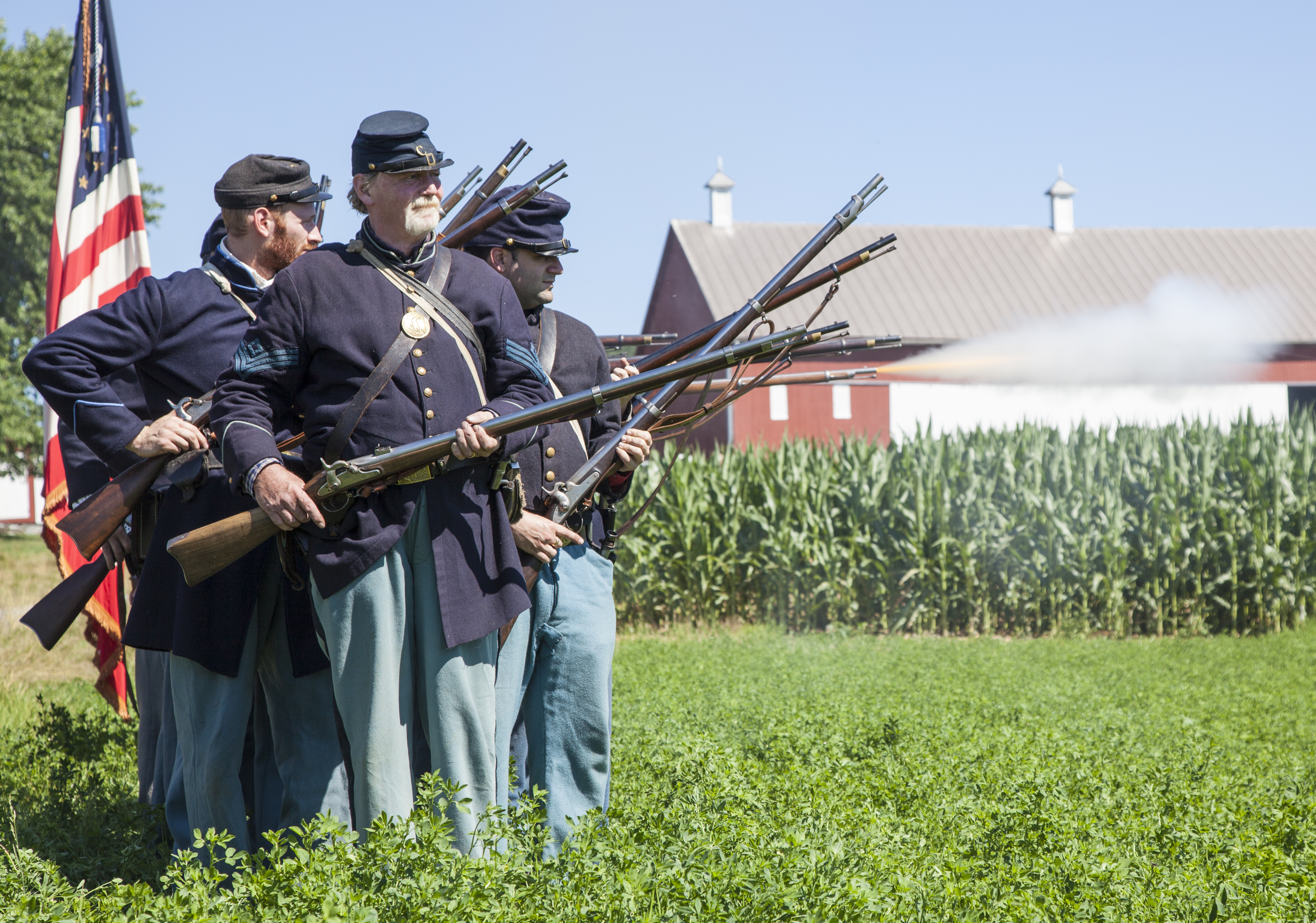 Living history volunteers demonstrate infantry firing muskets