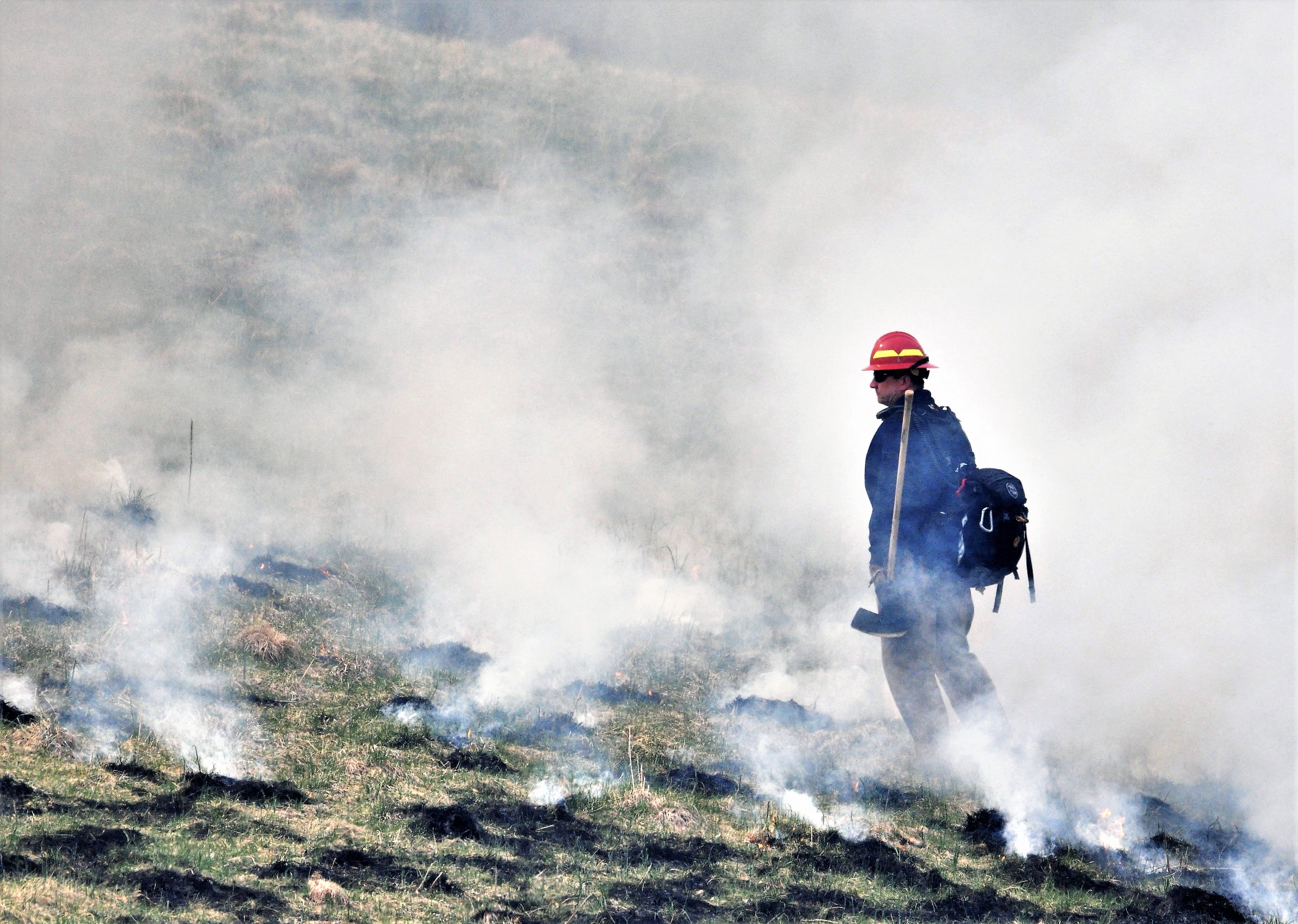 Smoke rises from burned spots of vegetation as a wildland fire watches for spot fires.