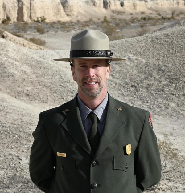 Derek Carter A man in a park ranger uniform standing on a gravel path
