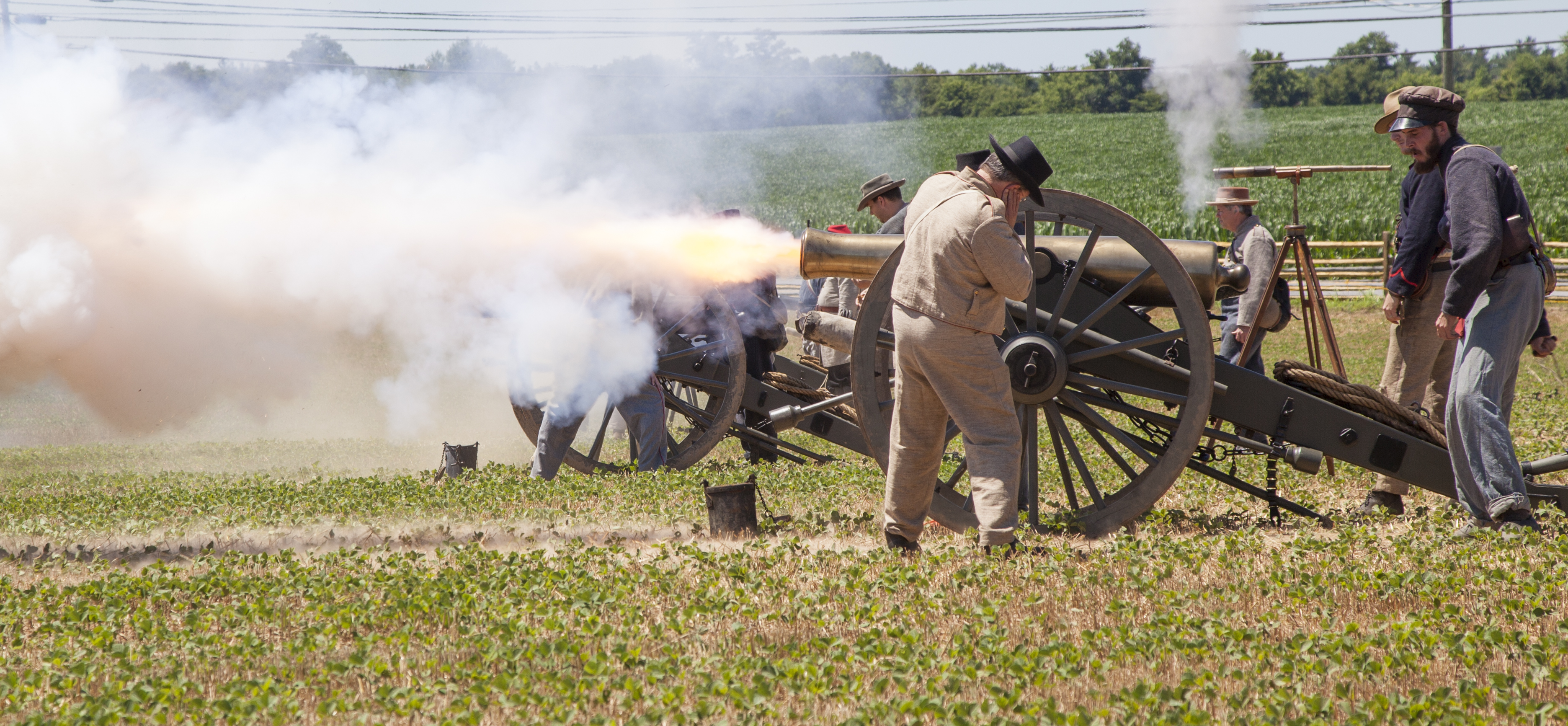 Smoke erupts from a cannon as volunteers dressed in Federal and Confederate Civil War uniforms turn away.