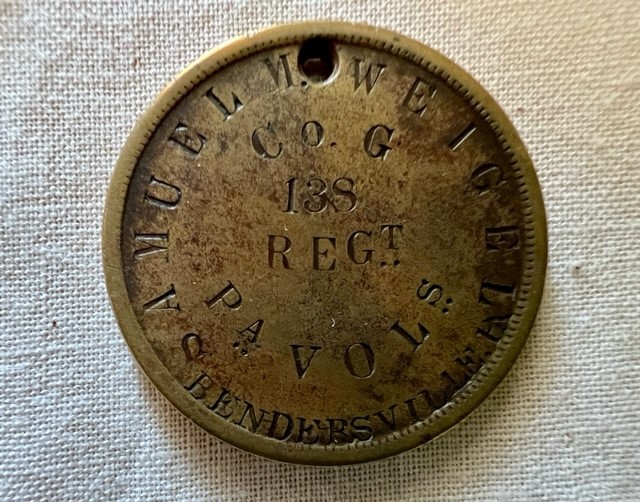 A small bronze disk stamped Samuel M. Weigel, Co. G, 138th Regt. PA Vols.