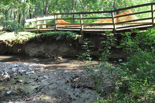 A boardwalk collapses into a stream due to undercutting.