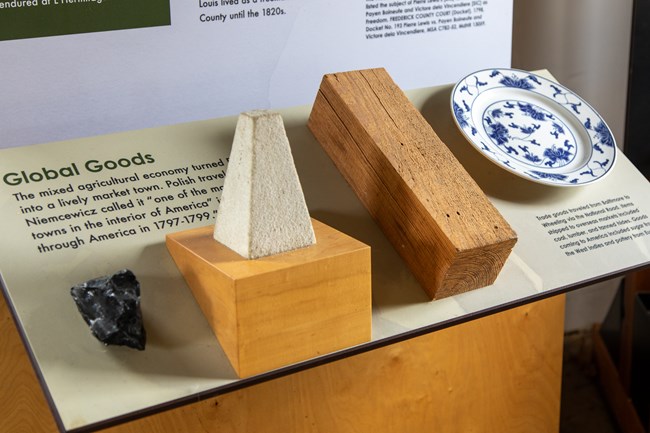 Stone, wood, and a plate attached to a museum exhibit panel with text.