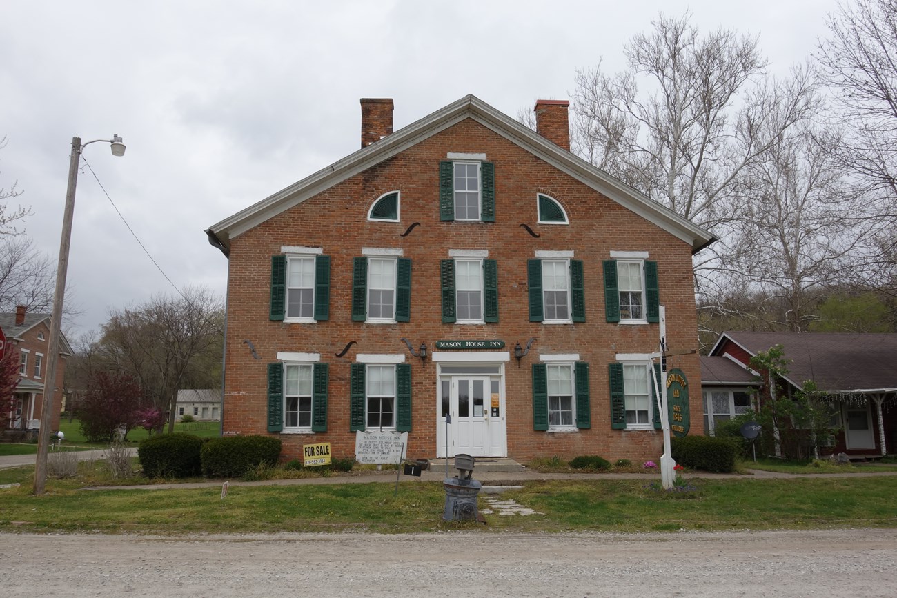 Mason House Inn in  Bentonsport, Iowa. Brick building with three stories and green shutters next to the windows.