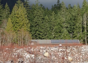 Solar panels on the roof a building surrounded by forest.