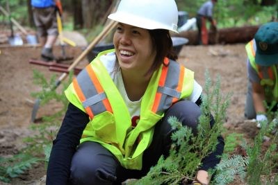 Young volunteer in safety gear plants vegetation.