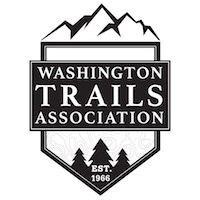 A black and white logo reading "Washington Trails Association" with icons of mountains above and trees below.