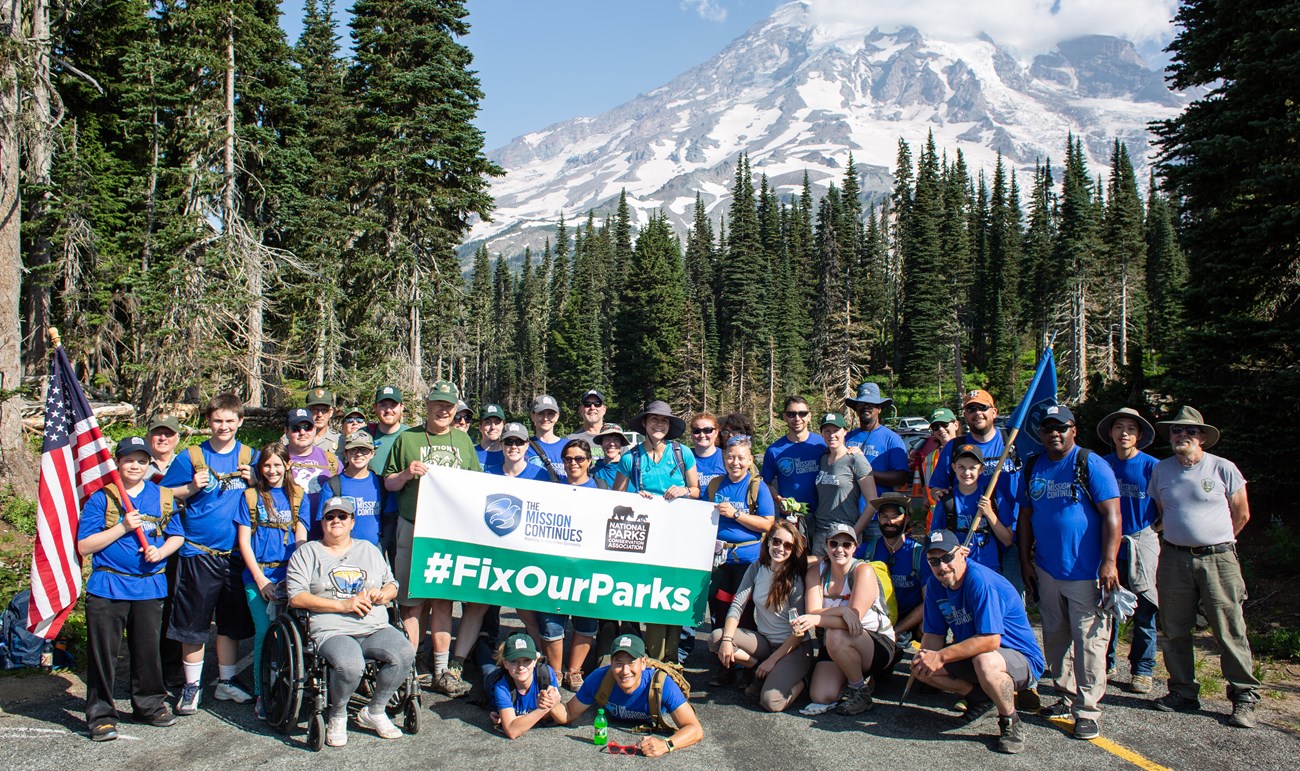 Group of volunteers pose in front of the mountain.