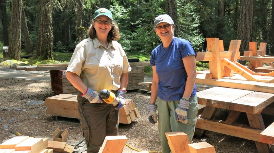 Two female volunteers build a picnic table.