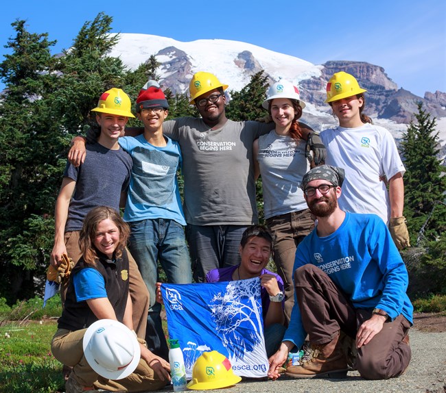 Group of youth volunteers poase in front of mountain.