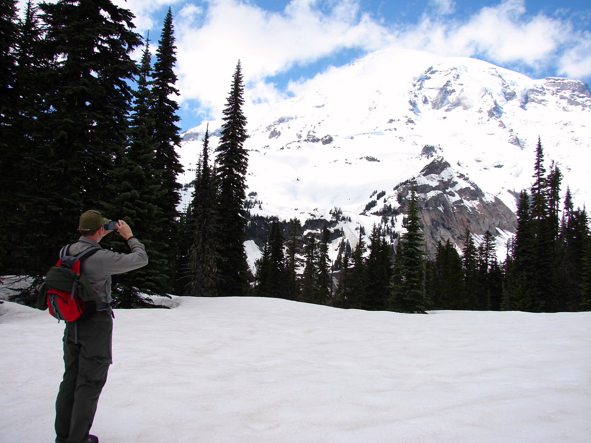 NPS/S. Redman photo of park ranger taking a photo of Mount Rainier.