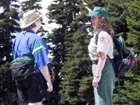 A meadow rover volunteer is talking to a visitor on a trail in the Paradise area. A meadow rover volunteer is talking to a visitor on a trail in the Paradise area.
