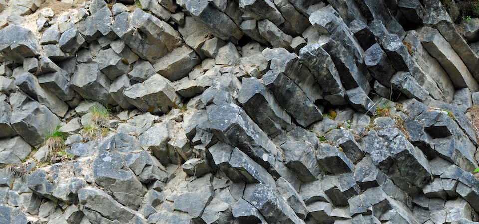 An exposed cluster of hexagonal rock columns in a hillside.