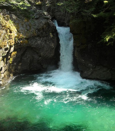 A short waterfall drops into a bright green pool.