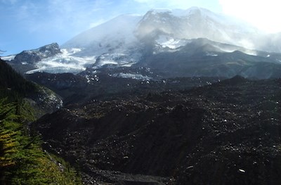 Looking up from the massive rock-covered terminus of Winthrup glacier towards the summit of Mount Rainier.