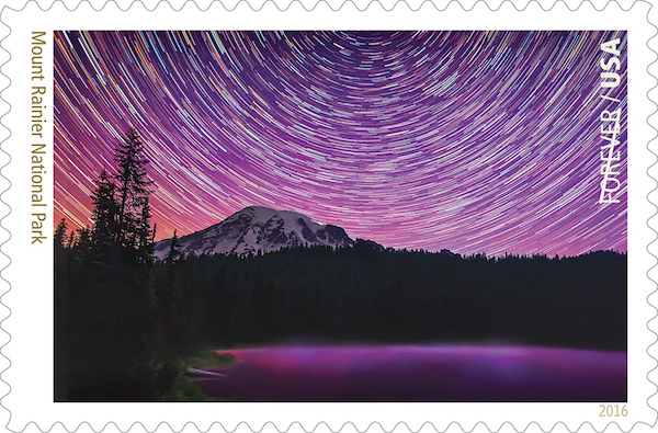 A stamp shows star trails swirling around Mount Rainier against a purple sky.