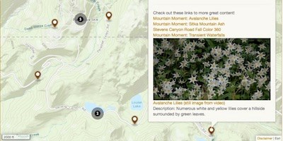 A portion of a map with points along a road. A pop-up from one point shows a picture of wildflowers and links to videos.