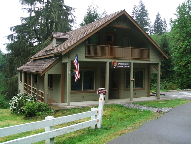 A green two-story building with pitched roof and adjacent parking lot.