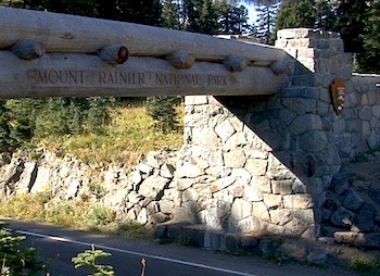 The large logs of the Chinook Entrance Arch stretch over the road, inset into rock foundations.