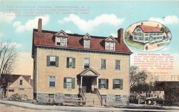 A colorized postcard of a 3 story tavern on a street with a orange roof, green shutters, windows, and a wide staircase leading to the front door.