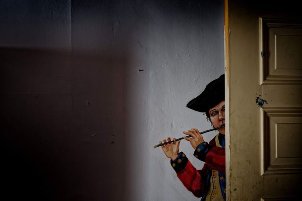 3 Cross Estate Mansion Room 304 - Photo Credit Xiomaro Wall painting of a young boy peering behind an actual open door, playing a fife and dressed as a Continental Army musician.