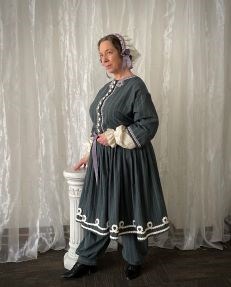 Theater actress Kim Hanley in a blue-gray period costume portraying American women's rights activist Elizabeth Cady Stanton.