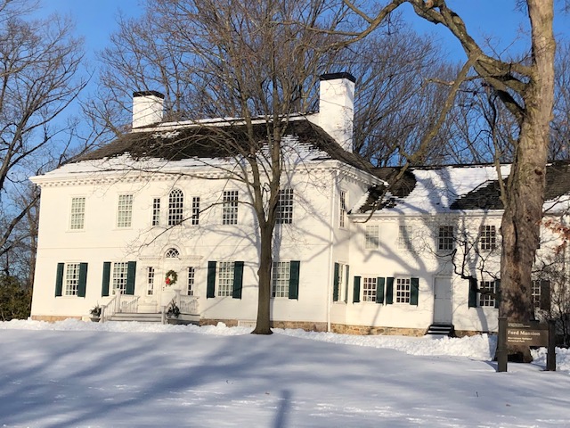 A white colonial mansion in the winter with snow