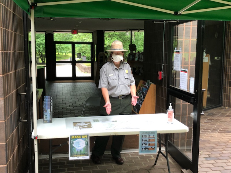 Ranger at a table in front of the Jockey Hollow Visitor center, waiting to greet visitors.