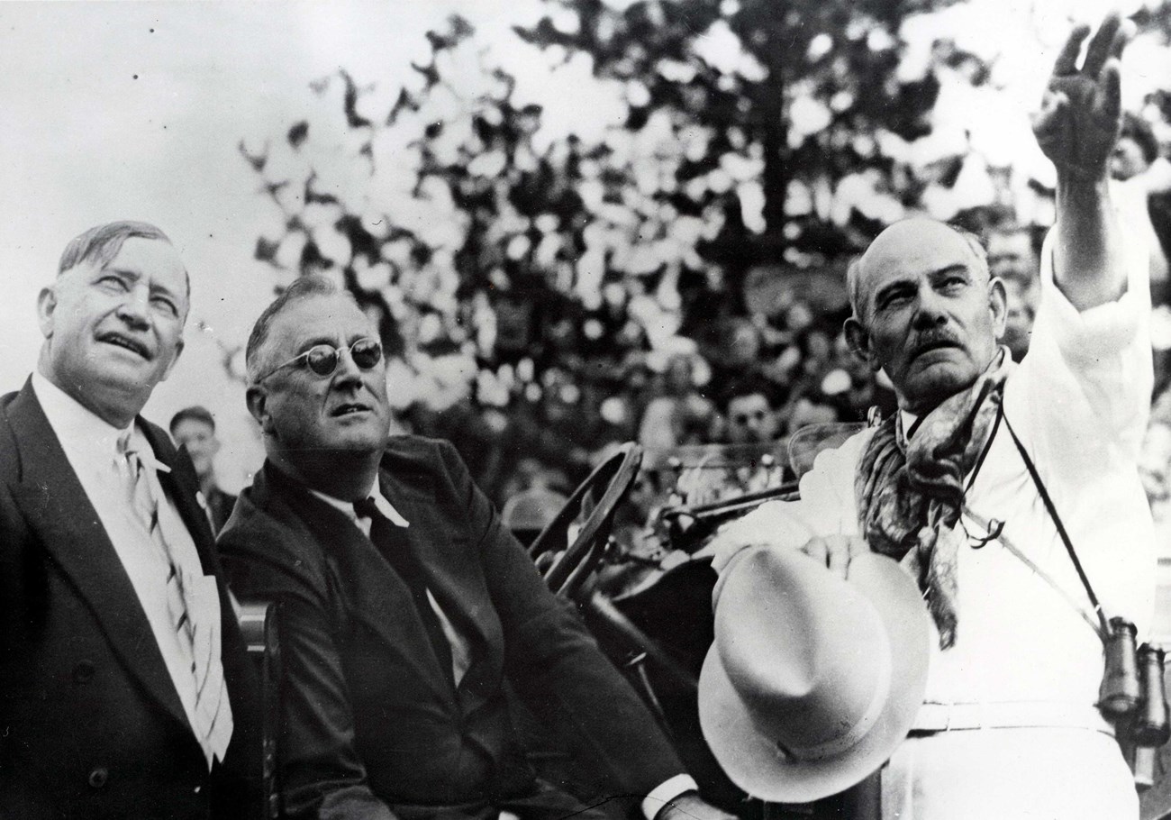 Black and white photo of South Dakota Governor Tom Berry (left), President Franklin D. Roosevelt (middle) and Gutzon Borglum (far right) at the 1936 unveiling of Thomas Jefferson. Berry and Roosevelt are looking up as Borglum points up and to the right.
