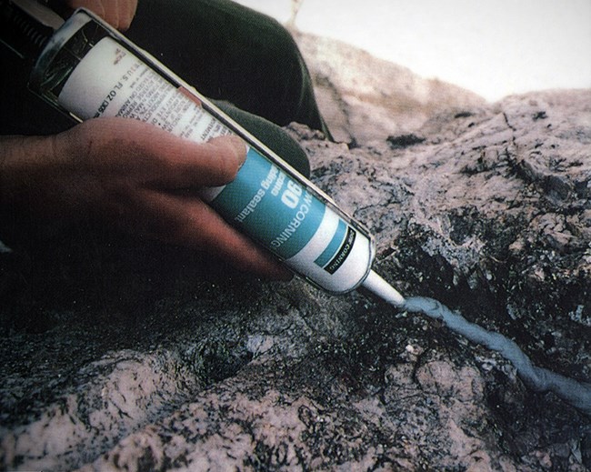 A worker applies silicone caulking to a crack on Mount Rushmore.