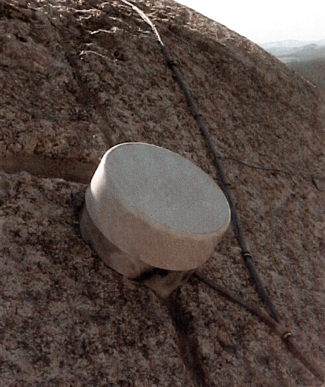 Photo of one of many round sensors on Mount Rushmore that continually monitor the granite for movement.