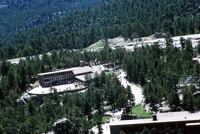 View from Mount Rushmore of the original Visitor Center in the upper left of the image and the Buffalo Dining Room and Gift Shop in the foreground in the lower right.  Both buildings faced towards the photographer.