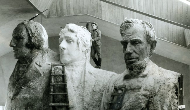 Lincoln Borglum standing on the scale plaster model with pointing equipment.  Theodore Roosevelt is not yet placed on this model.