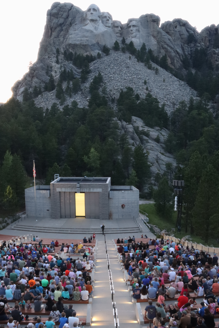 Visitors in the amphitheater for the evening program, with Mount Rushmore in the background. Visitors in the amphitheater for the evening program, with Mount Rushmore in the background.