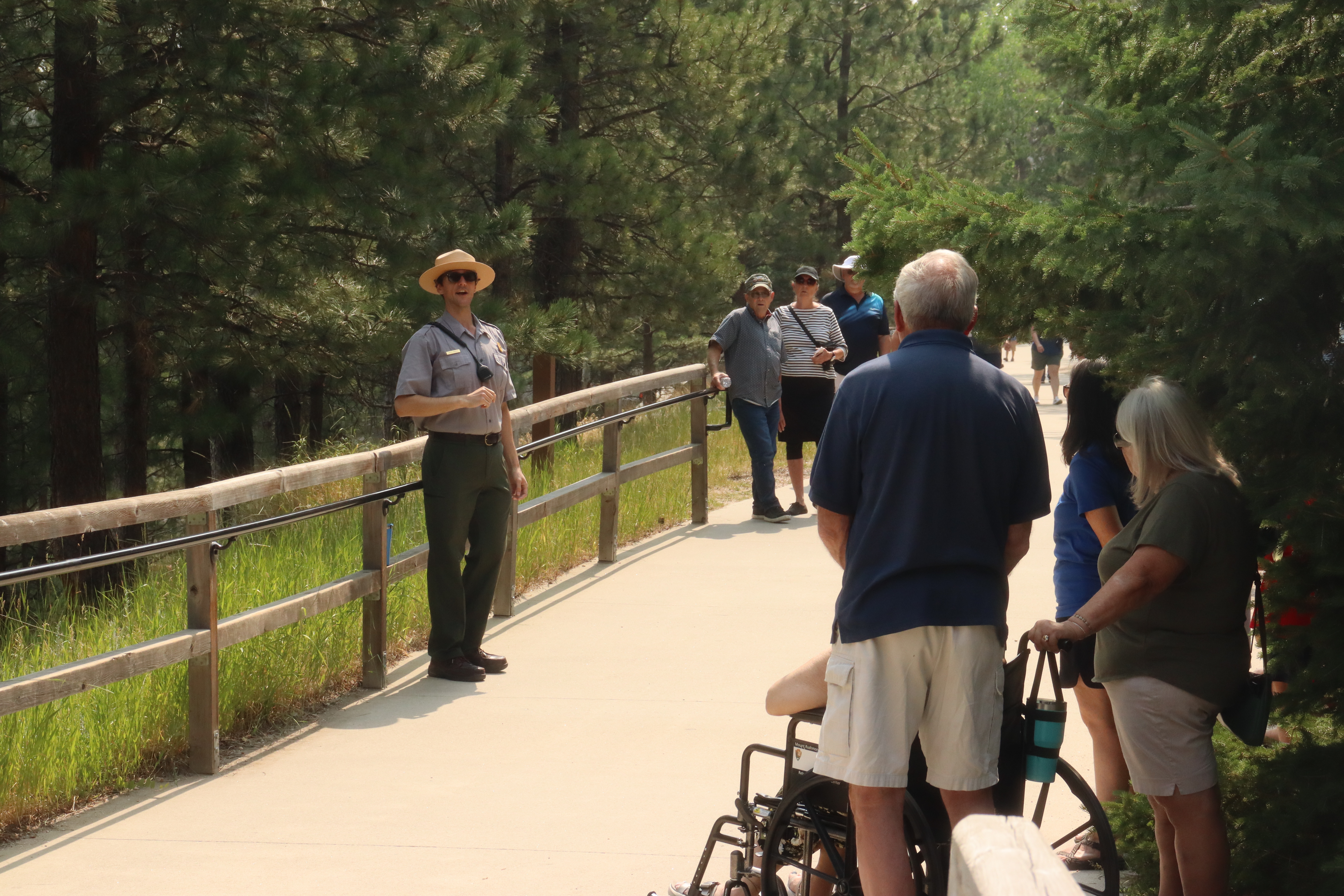A ranger speaking to a crowd of visitors along a park trail.