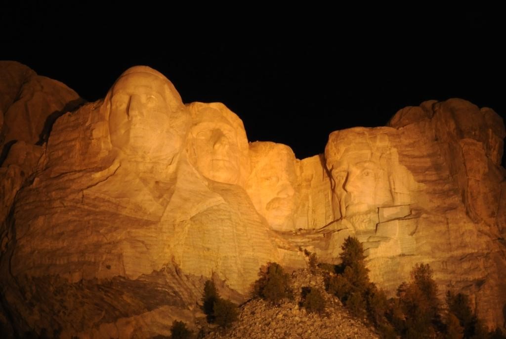 Photograph of Mount Rushmore illuminated at night.