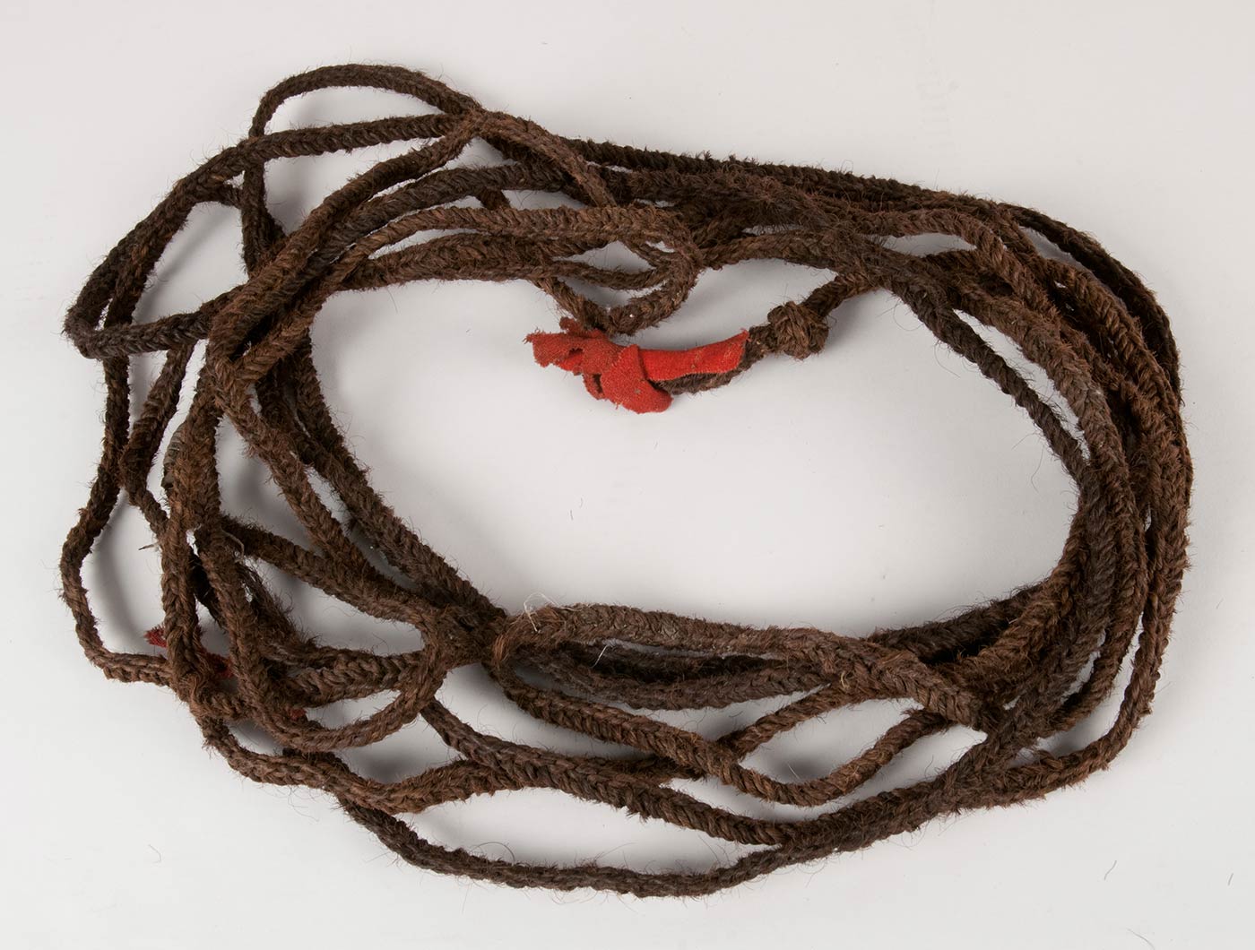Woven bison hair rope with knotted ends decorated with red wool broadcloth
