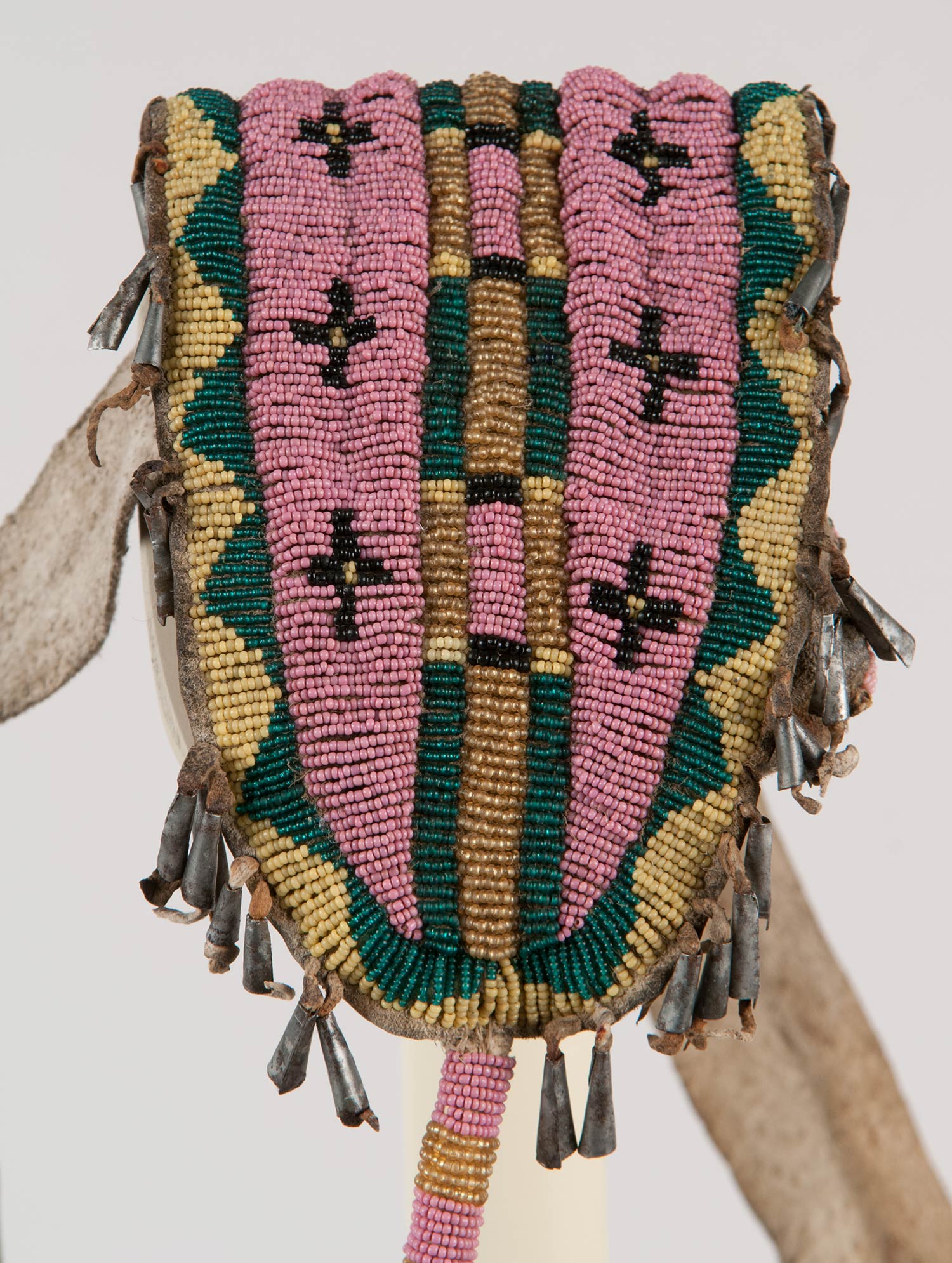 Beaded and tin cone pouch attached to a bison hide belt.