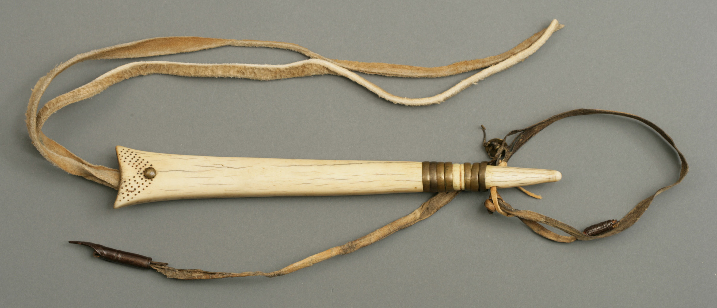 Decorated elk antler horse quirt or whip. The handle is formed of a piece of rawhide thong to which a forged iron ram rod is attached at one end. 