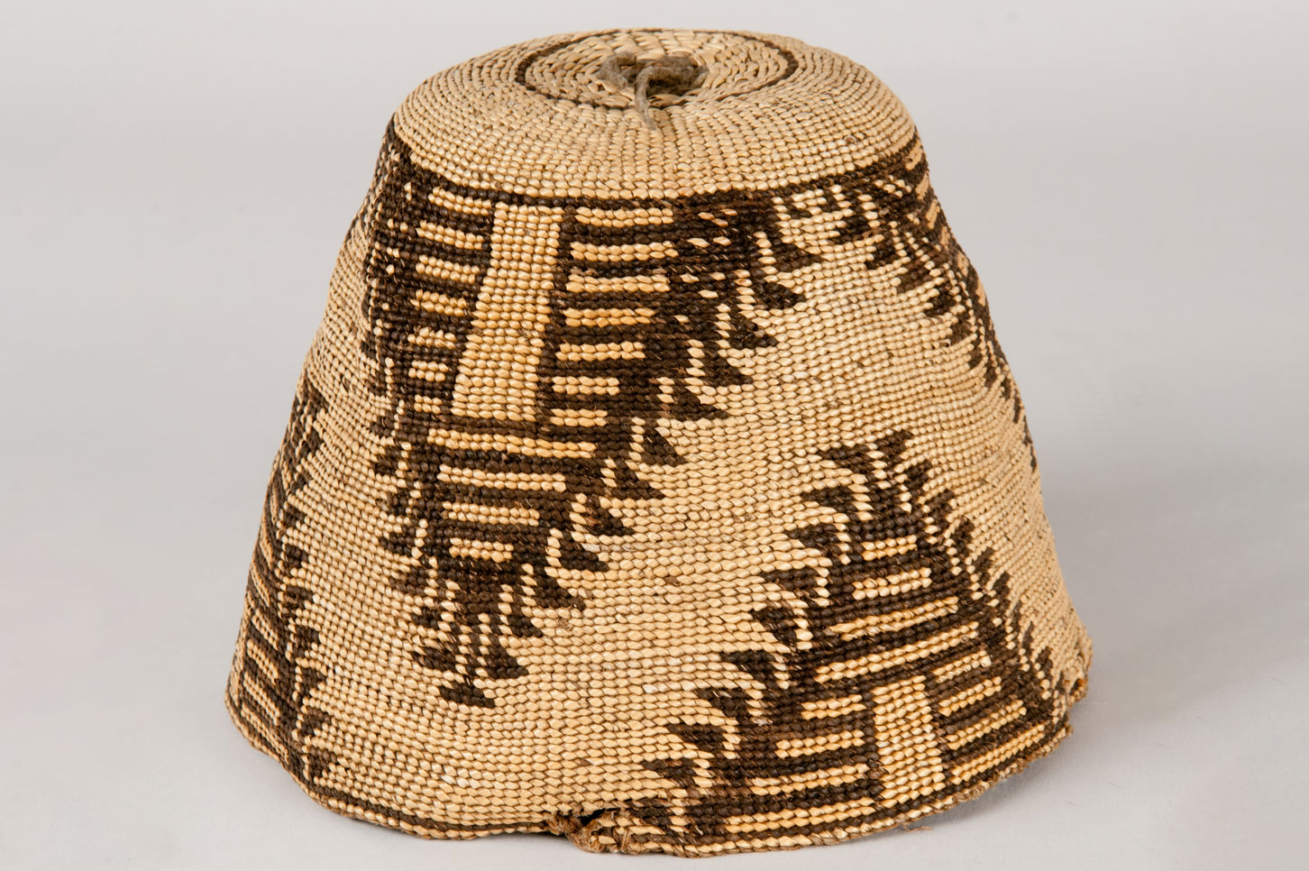 Subconical shaped basket hat made from hemp and beargrass. Designs on the hat feature a three part separated pyramid with horizontal banding on the interior in orange and dark brown.