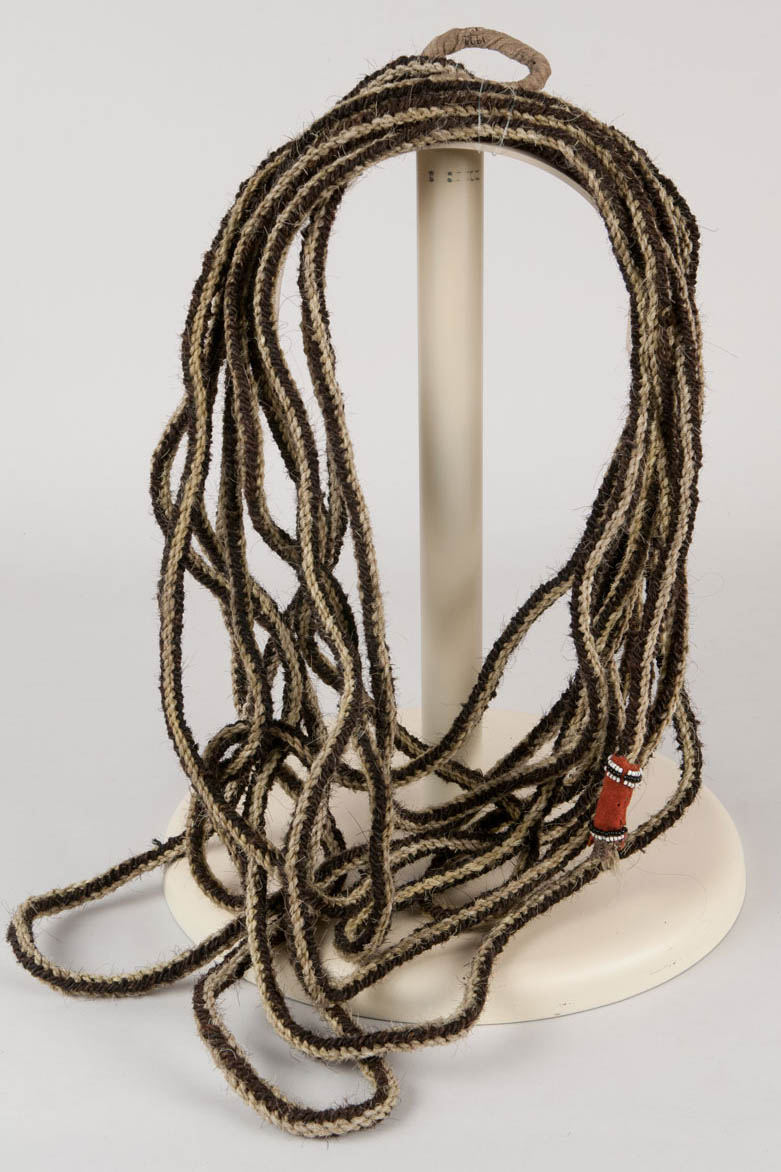Woven horse hair rope with red wool cloth decorated ends. Rope weaving is formed of eight tightly twisted strands with two edges formed of each color.