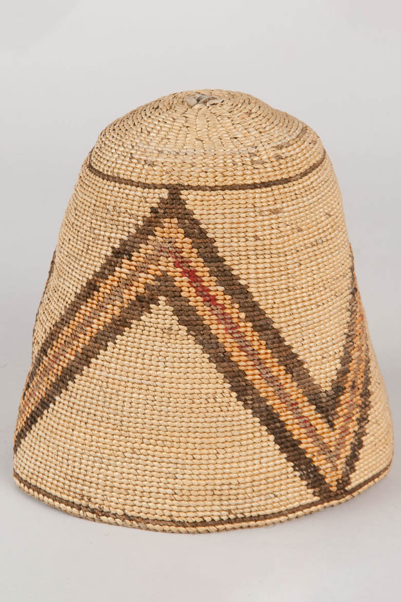 Subconical shaped basket hat made from hemp, beargrass, cedar root bark strips, and wool. Piece of cured hide located at top of hat, which was used to start the crown base.