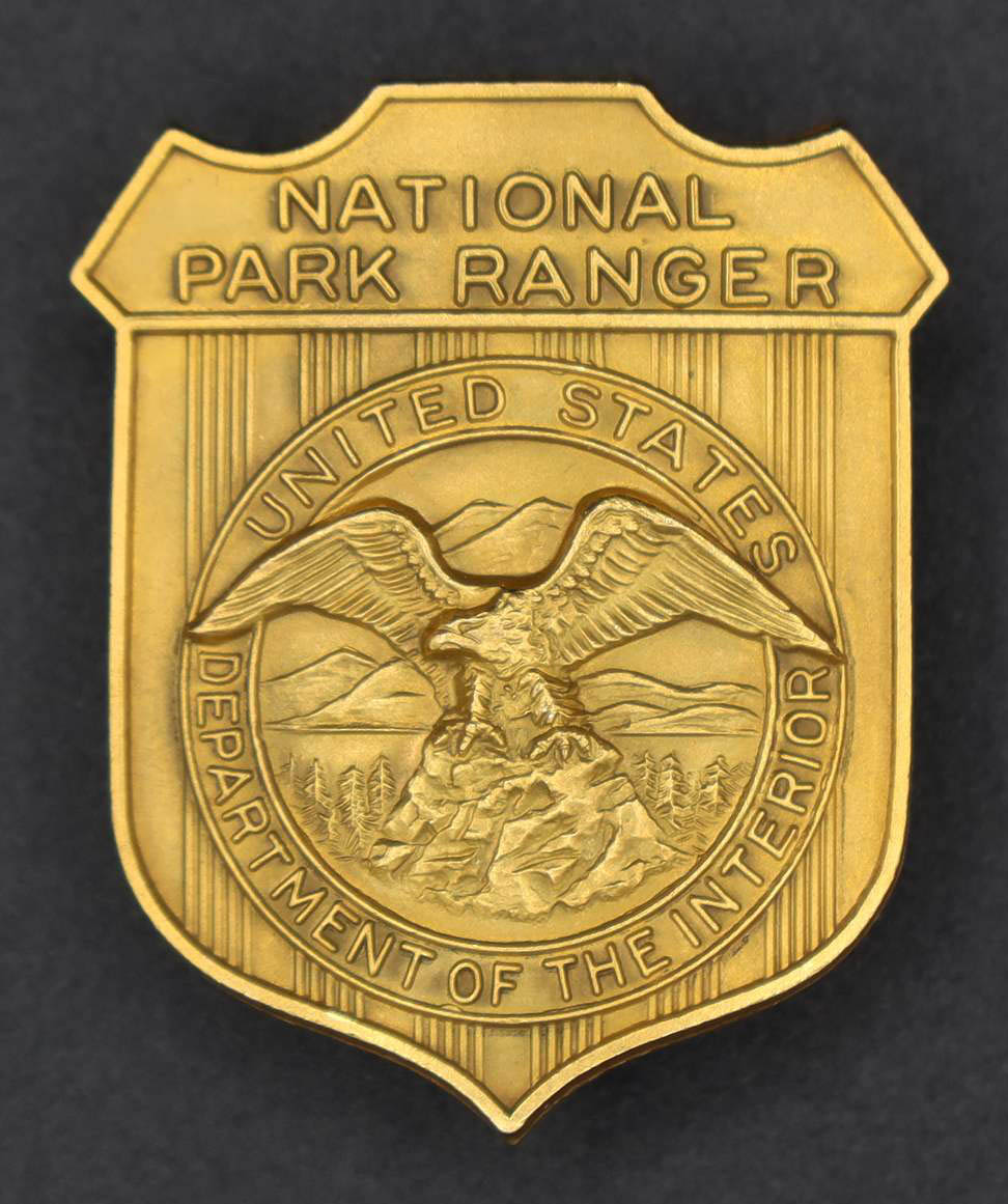 Gold shield-shaped badge marked National Park Ranger. The round seal in the middle has an eagle looking to its right.