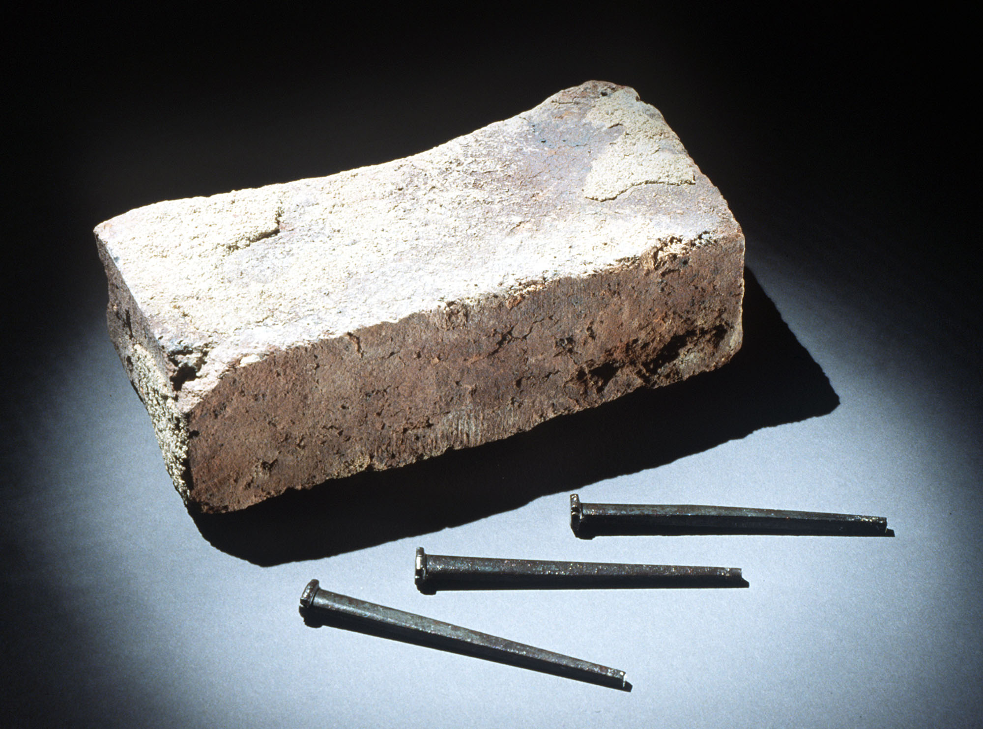 Photograph shows a brick that was removed from Tompkins Hall, Tuskegee Institute, Alabama and nails made by students at Tuskegee Institute to build its chapel