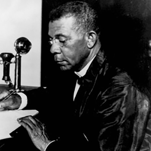 Booker T. Washington sitting at his desk writing