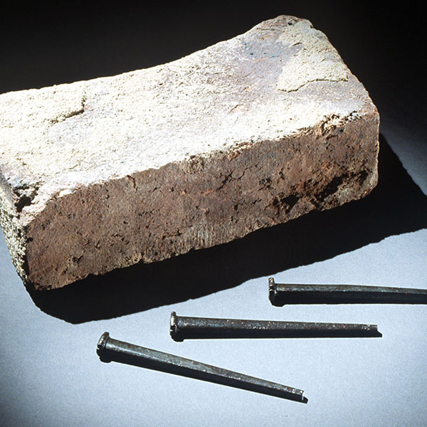 Photograph shows a brick that was removed from Tompkins Hall, Tuskegee Institute, Alabama and nails made by students at Tuskegee Institute to build its chapel