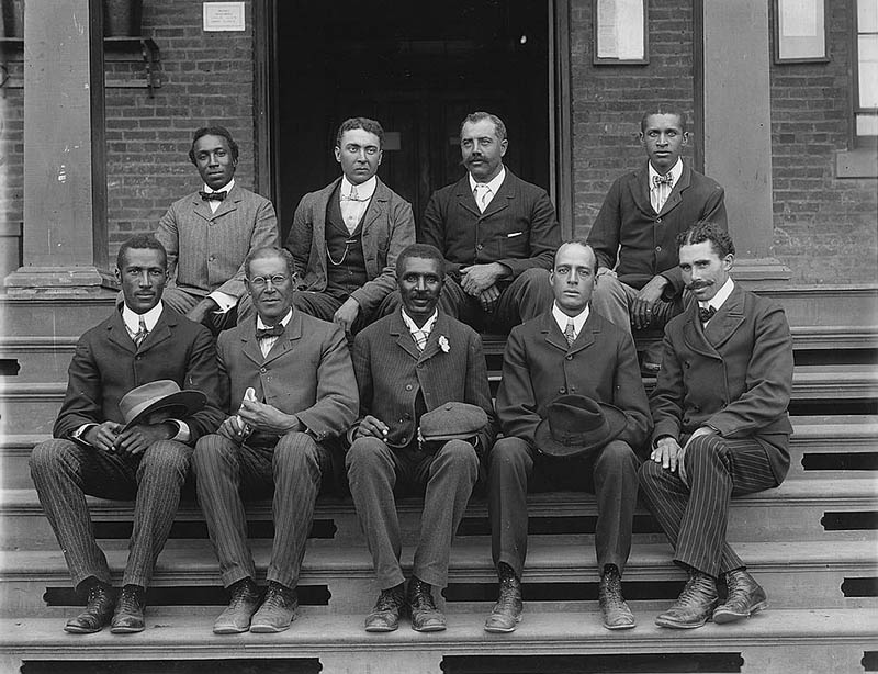 George Washington Carver, full-length portrait, standing in field, probably at Tuskegee, holding piece of soil