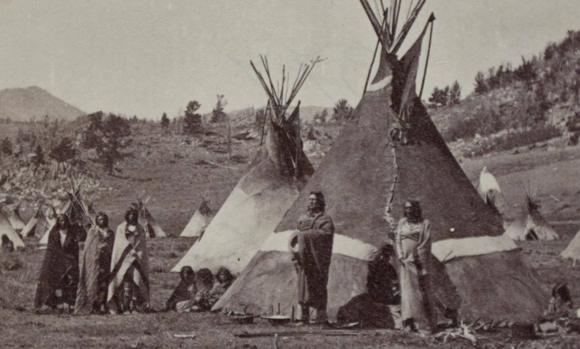 Native Americans standing around Tipis